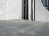 an empty courtyard with the doors open on a building side view of this building has a large wall with two vertical columns at one end and there is a hole in front