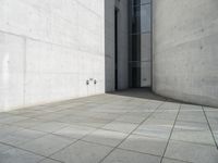 an empty courtyard with the doors open on a building side view of this building has a large wall with two vertical columns at one end and there is a hole in front