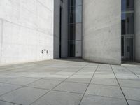 an empty courtyard with the doors open on a building side view of this building has a large wall with two vertical columns at one end and there is a hole in front