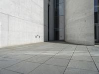 an empty courtyard with the doors open on a building side view of this building has a large wall with two vertical columns at one end and there is a hole in front