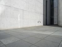 an empty courtyard with the doors open on a building side view of this building has a large wall with two vertical columns at one end and there is a hole in front