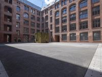 an empty courtyard with a bunch of windows in it in front of a building on the opposite side