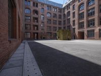 an empty courtyard with a bunch of windows in it in front of a building on the opposite side
