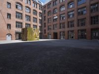 an empty courtyard with a bunch of windows in it in front of a building on the opposite side