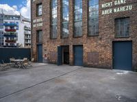 the empty courtyard with wooden tables and chairs is shown in a photograph with red brick walls