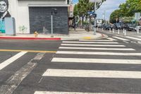 the white painted crosswalk on the street is empty and the sky is blue and the yellow line is painted with an image of an old man on the painting