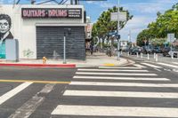 the white painted crosswalk on the street is empty and the sky is blue and the yellow line is painted with an image of an old man on the painting