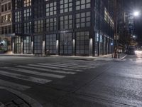 an empty crosswalk at night in a city with lights on and skyscrapers lit up