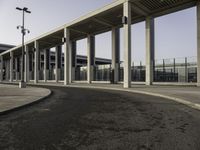 the curved asphalt pathway is empty and concreted near the station entrance of an industrial building