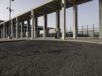 the curved asphalt pathway is empty and concreted near the station entrance of an industrial building