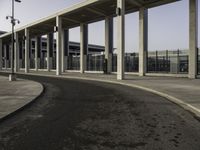 the curved asphalt pathway is empty and concreted near the station entrance of an industrial building