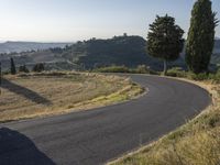 a curved road is empty with no cars or people on it that has trees and hills