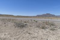 an empty desert field next to a dirt road in a valley with mountains and trees