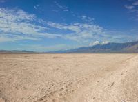 an empty desert landscape in the desert under a blue sky with clouds and mountains in the distance