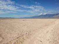 an empty desert landscape in the desert under a blue sky with clouds and mountains in the distance