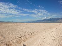 an empty desert landscape in the desert under a blue sky with clouds and mountains in the distance