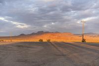 an empty empty desert with a telephone pole in the middle of it that has hills and a few clouds