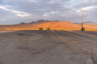 an empty empty desert with a telephone pole in the middle of it that has hills and a few clouds