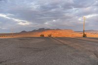 an empty empty desert with a telephone pole in the middle of it that has hills and a few clouds