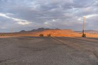 an empty empty desert with a telephone pole in the middle of it that has hills and a few clouds