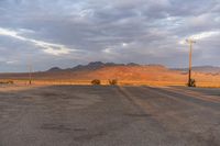 an empty empty desert with a telephone pole in the middle of it that has hills and a few clouds