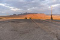 an empty empty desert with a telephone pole in the middle of it that has hills and a few clouds