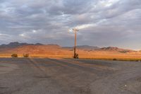 an empty empty desert with a telephone pole in the middle of it that has hills and a few clouds