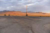 an empty empty desert with a telephone pole in the middle of it that has hills and a few clouds