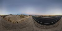 an empty desert road with no cars on it at sunset with no lights visible in the sky