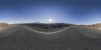 an empty desert road in the middle of nowhere and a mountain range in the background