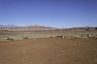 an empty dirt field with mountains in the distance in the desert under a blue sky