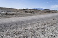 a dirt road is surrounded by some hills and desert like terrain as the vehicle sits on it