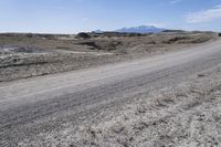 a dirt road is surrounded by some hills and desert like terrain as the vehicle sits on it