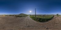 a fish - eye lens shot of an empty dirt road and field in the background