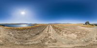 a panorama lens shot of an empty dirt road, showing the sun in the sky