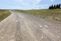 the dirt road is empty and full of cars and grass on either side of it