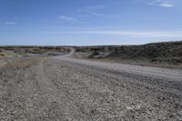 a dirt road is surrounded by some hills and desert like terrain as the vehicle sits on it