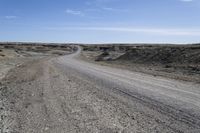 a dirt road is surrounded by some hills and desert like terrain as the vehicle sits on it