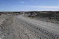 a dirt road is surrounded by some hills and desert like terrain as the vehicle sits on it