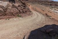 the dirt road is empty in the mountains near rocks and grass along the edge of a narrow path