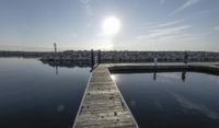 the dock is empty with rocks in the background as the sun is setting over the water