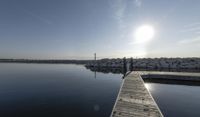 the dock is empty with rocks in the background as the sun is setting over the water