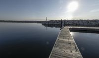 the dock is empty with rocks in the background as the sun is setting over the water