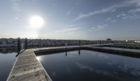 the dock is empty with rocks in the background as the sun is setting over the water