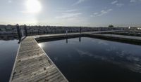 the dock is empty with rocks in the background as the sun is setting over the water