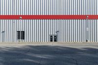 a view of some doors at a building's entrance that is empty outside and has red painted siding