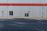 a view of some doors at a building's entrance that is empty outside and has red painted siding