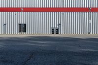 a view of some doors at a building's entrance that is empty outside and has red painted siding