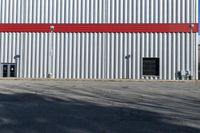 a view of some doors at a building's entrance that is empty outside and has red painted siding