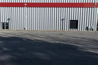 a view of some doors at a building's entrance that is empty outside and has red painted siding